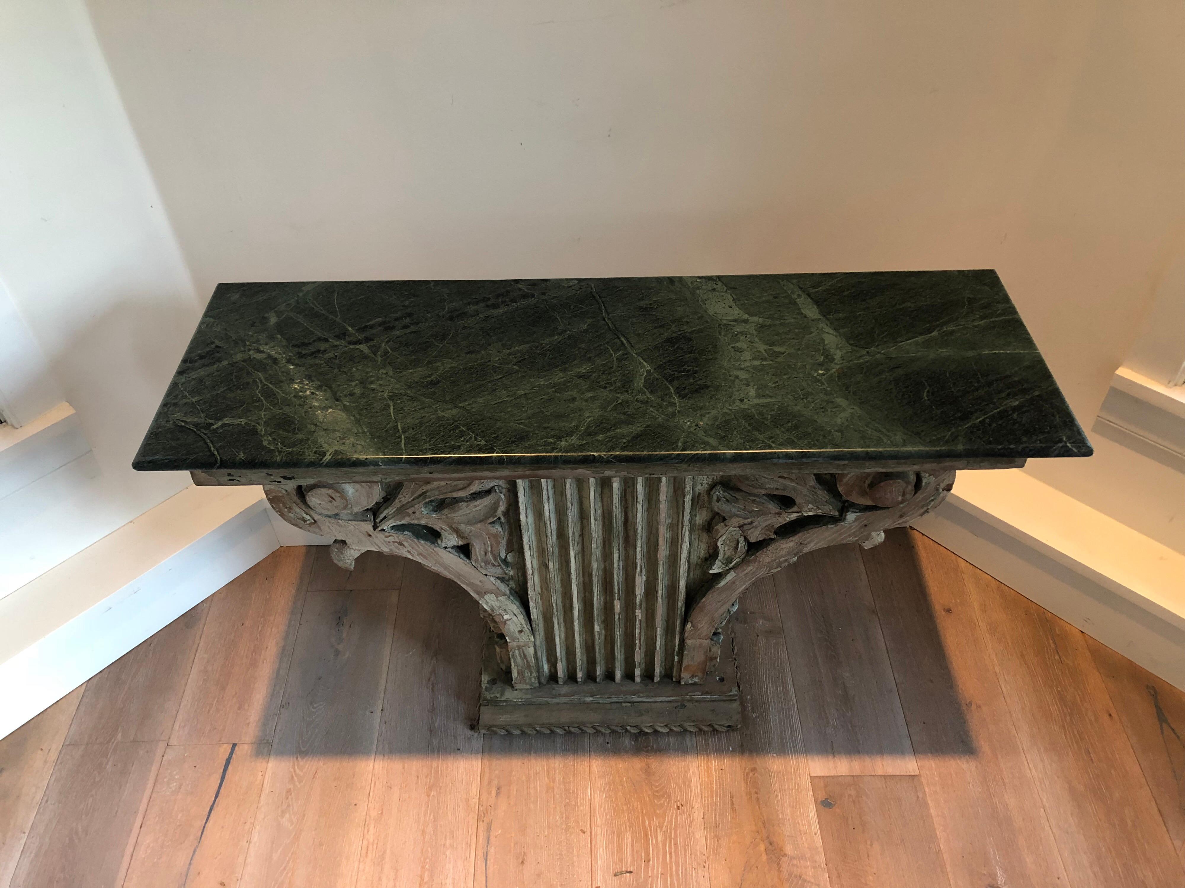 An antique architectural wood fragment now as a console table. With green marble top. Overall distressed finish to base. Decorated on all 4 sides.