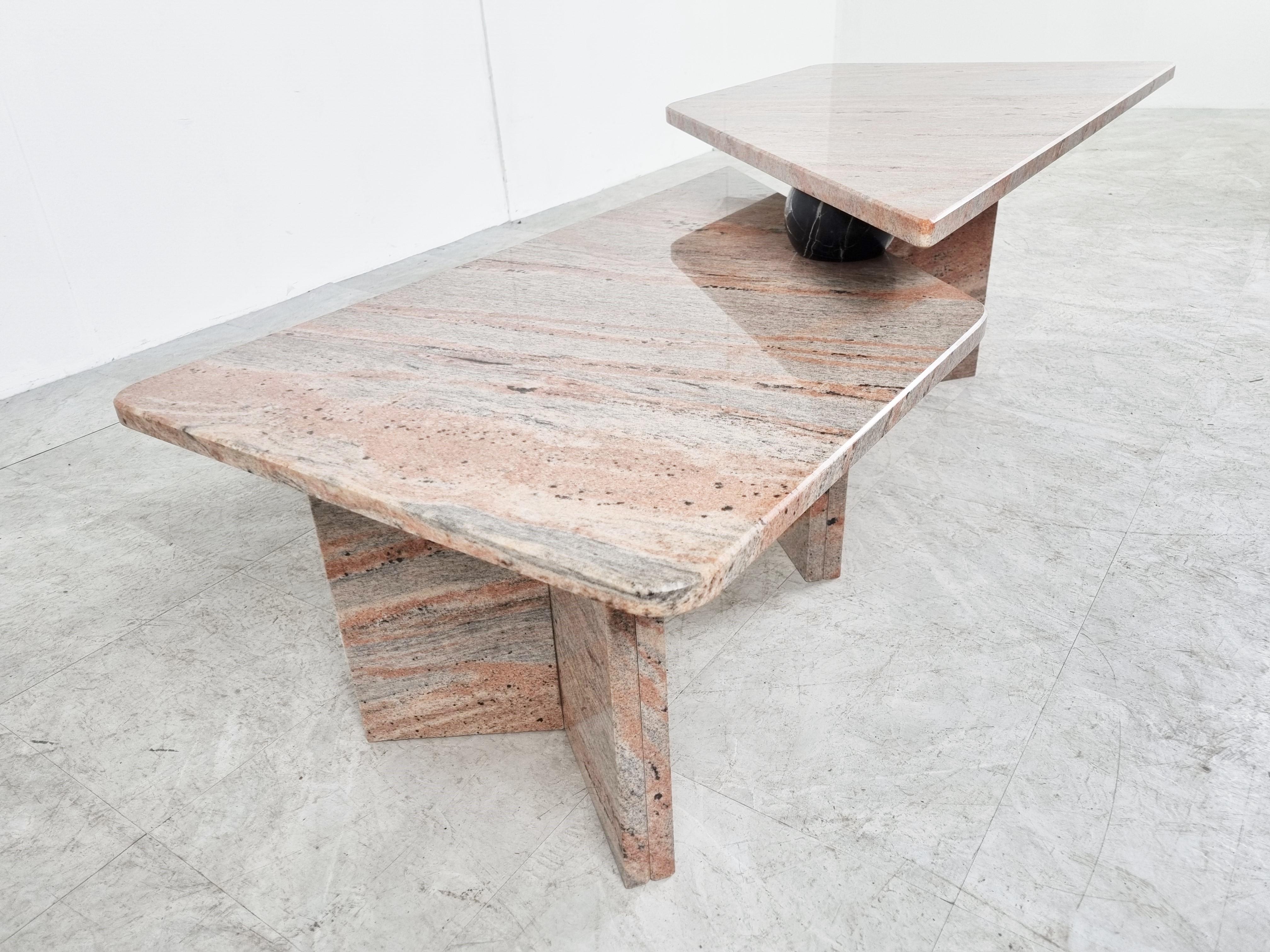 Architectural coffee table made from red/orange granite stone.

The coffee table consists of two parts which rest on each other trough the black marble 'sphere'.

The vaining in the stone is beautiful and the rare colour also makes this table