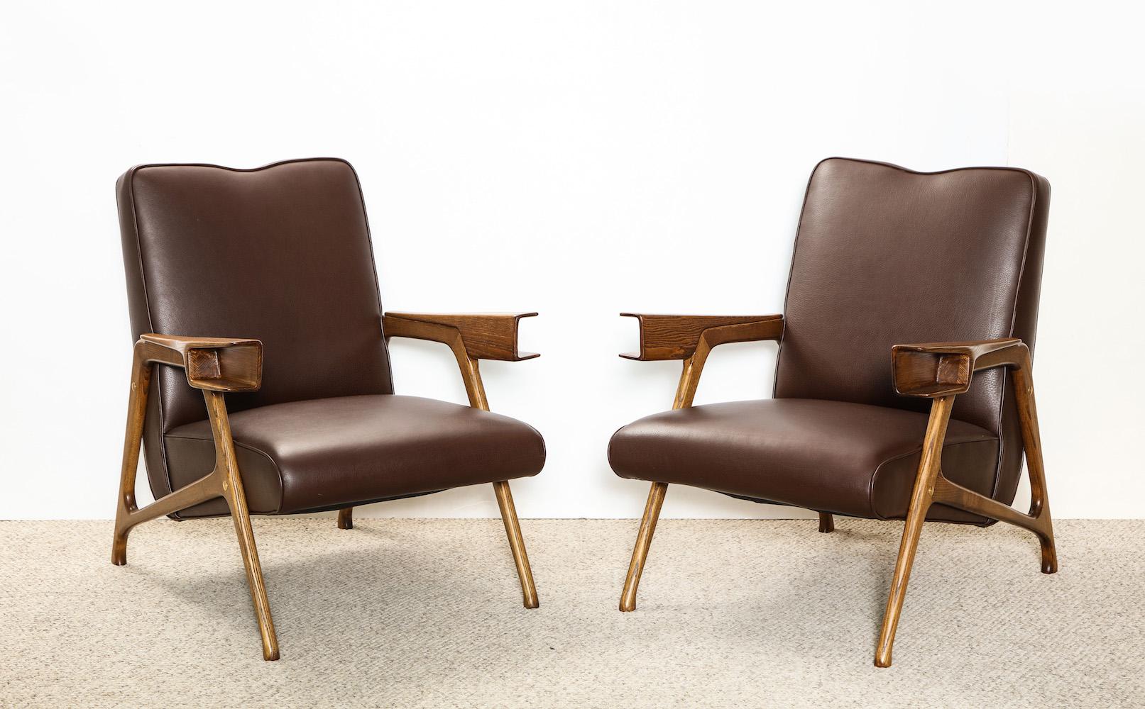 Architectural pair of lounge chairs attributed to Augusto Romano. Solid oak architectural frame, with brown leather upholstered seat and back. Fantastic detailing and strong look.
  