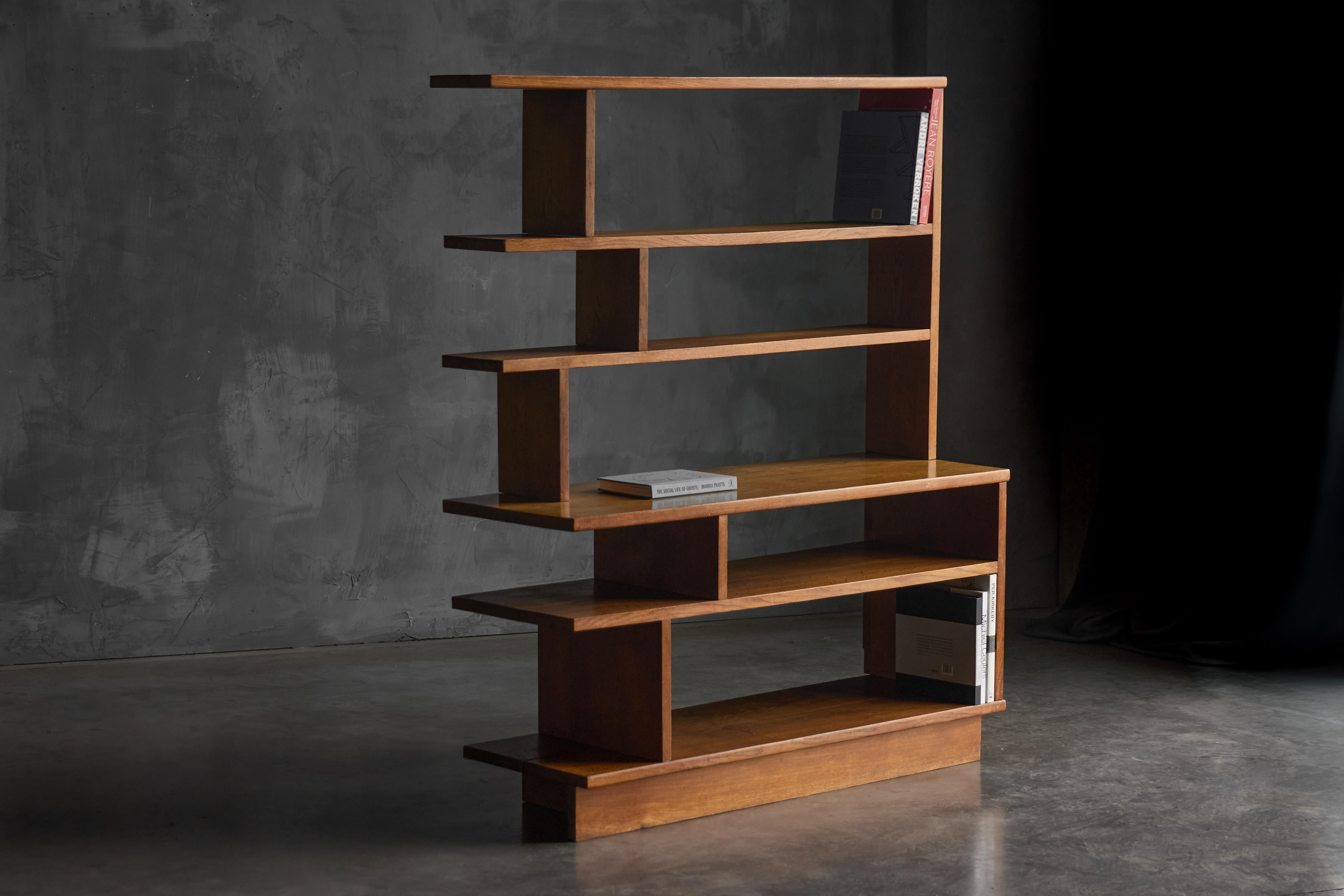 Una libreria scultorea di metà secolo che unisce architettura e artigianato. Realizzato in legno dai toni intensi, i suoi ripiani asimmetrici creano un gioco ritmico di proporzioni e luce. Progettato per fungere sia da libreria che da divisorio, il
