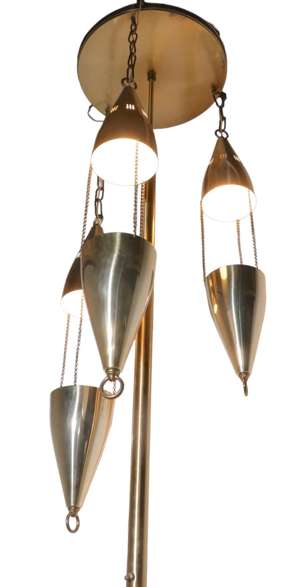 Chic architectural mid century tension pole lamp, with three pendant lights. The lamp is in brass finish, it is in exceptional, original, clean and working condition, ready to install. The lamp runs from the floor to the ceiling and stays vertical