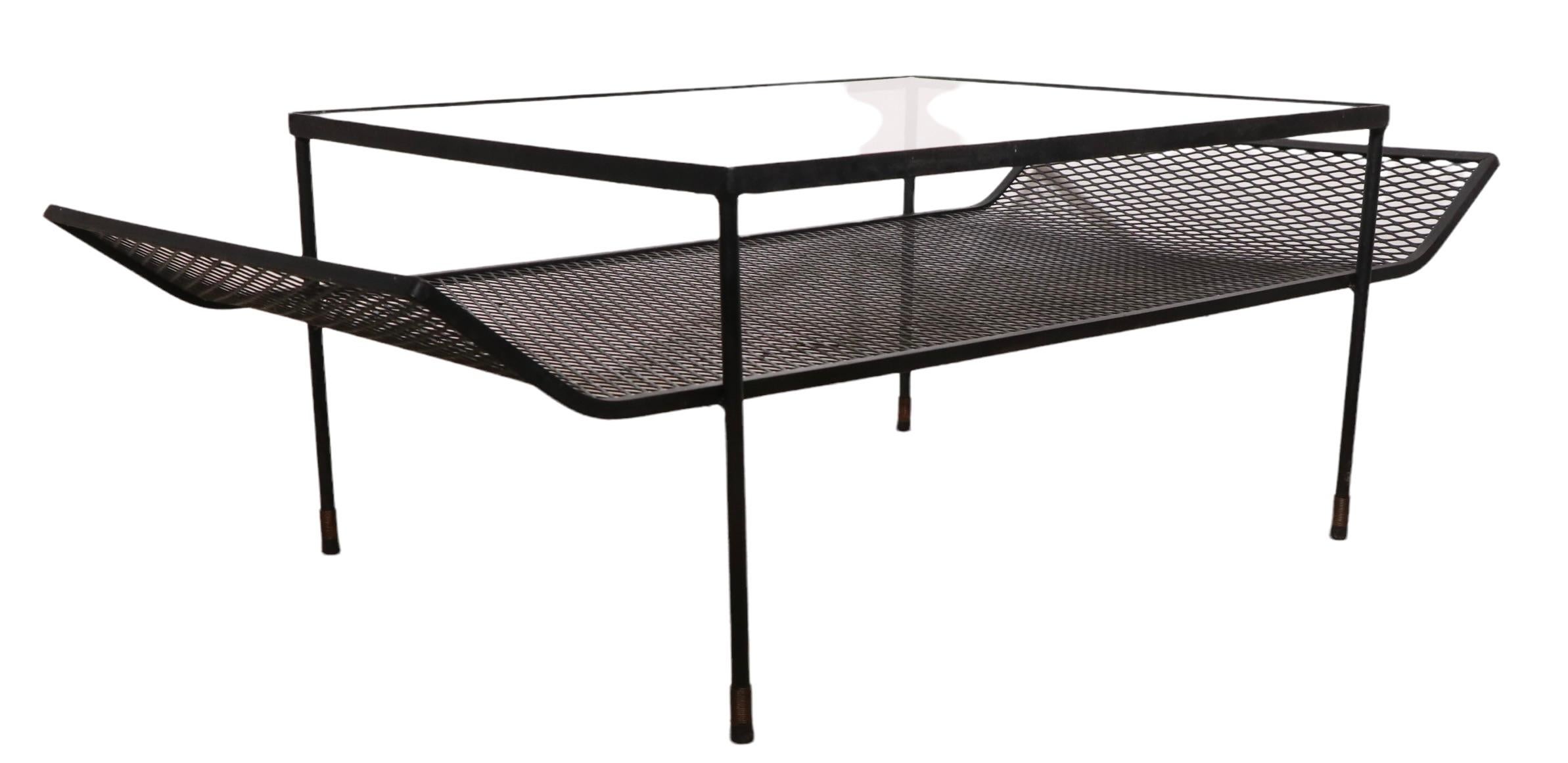 Architectural mid-century wrought iron, metal mesh and glass top coffee, cocktail table, attributed to Woodard, in the style of Paul McCobb, George Nelson etc. The table features a rectangular glass top surface, over an extended metal mesh lower