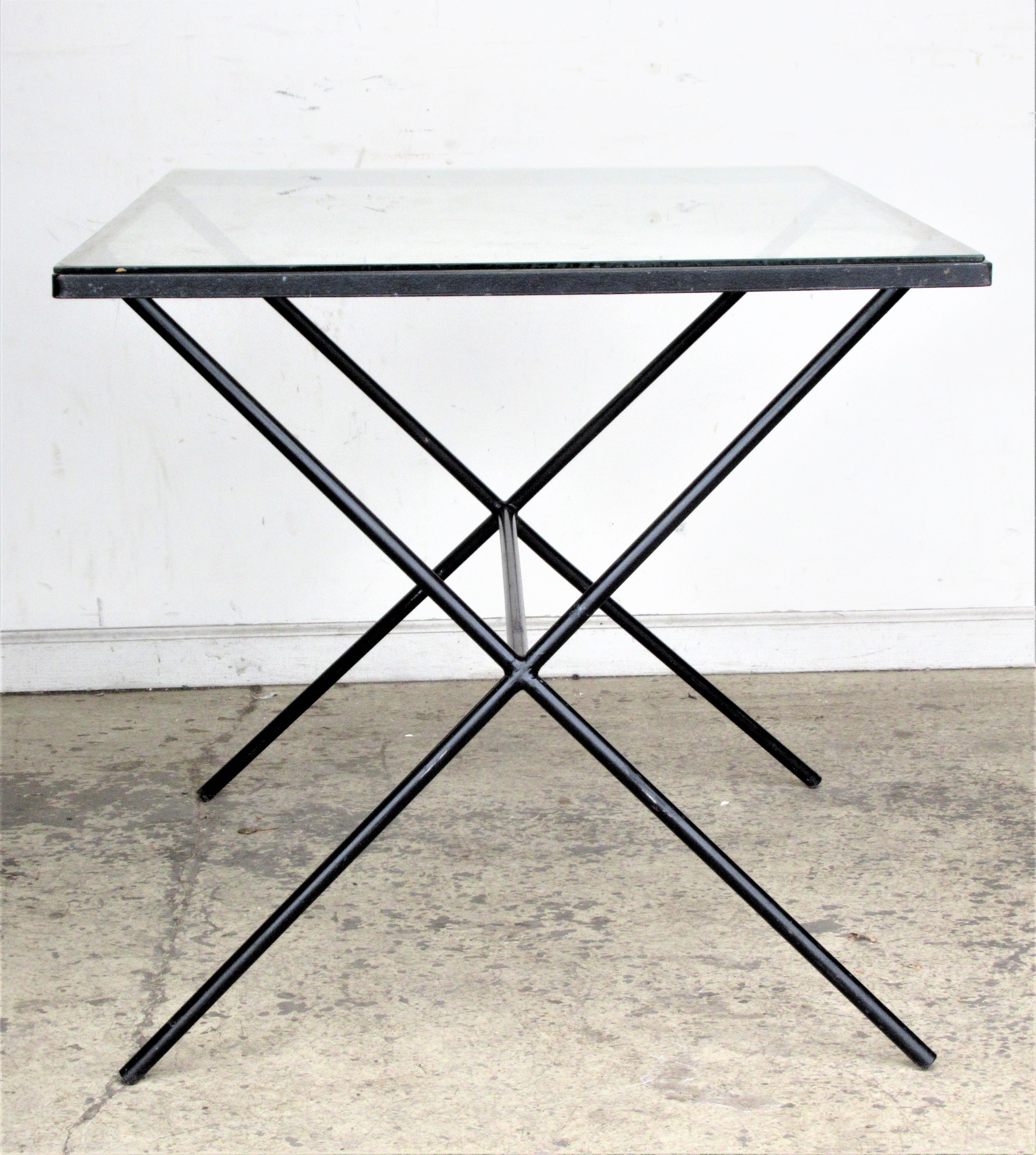 Architectural modernist iron and glass top dining table with tubular iron X-form subtly splayed legs joined by a long central stretcher. Designed by Muriel Coleman ( California, 1917-2003 ) for Pacific Iron Works, circa 1950. This is a beautiful