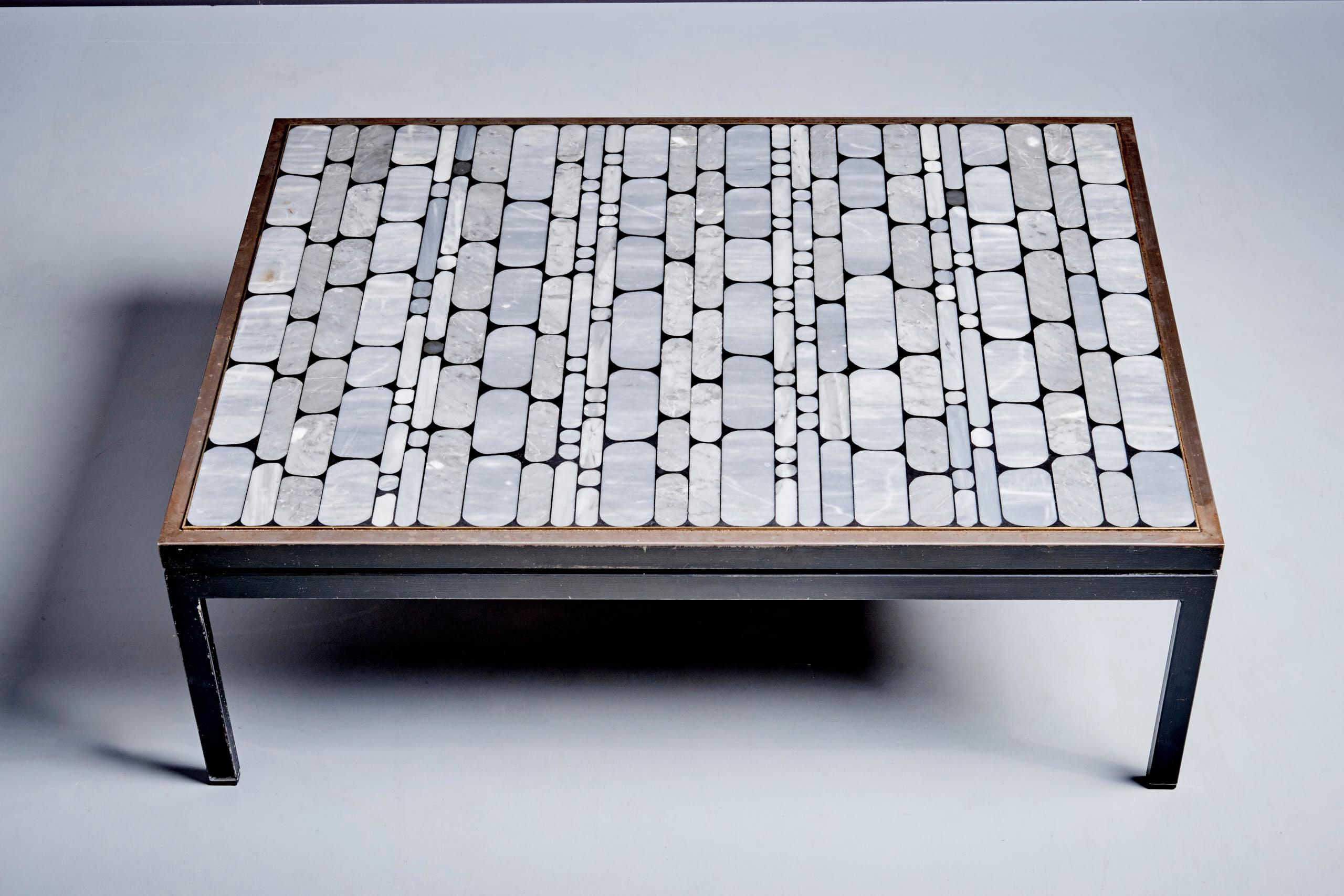 Table basse avec plateau en mosaïque de marbre Table basse rectangulaire avec plateau en mosaïque de carreaux de marbre gris et blanc, disposés en rangées dans un cadre métallique. Soutenu par une base carrée en métal peint en noir avec des pieds