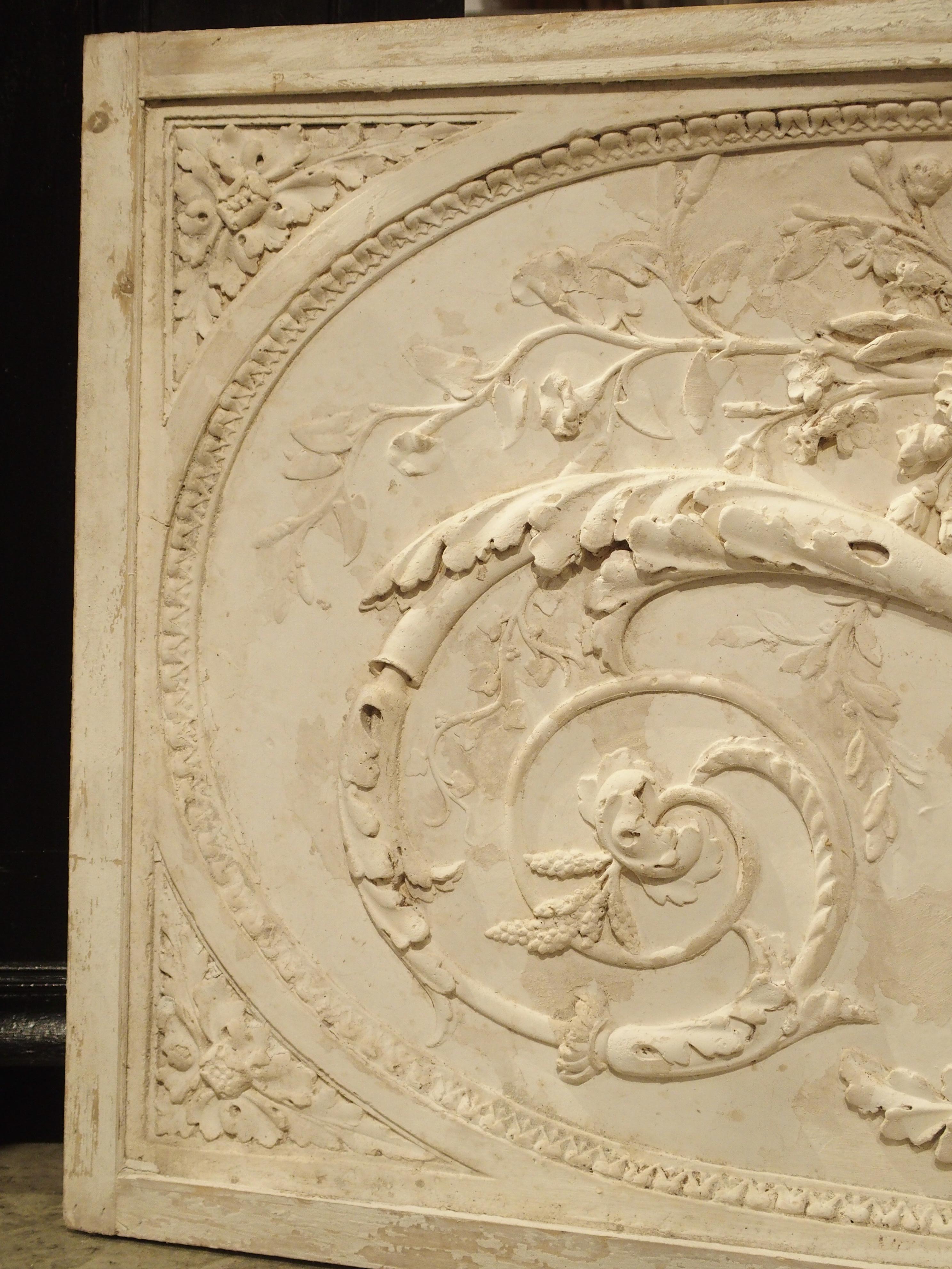 This beautiful panel is a parcel paint plaster bas relief from France. The framed plaster overdoor depicts Classic scrolling rinceau growing from a central vase. Originally, these were placed over doors in French paneled rooms. Today, they can still