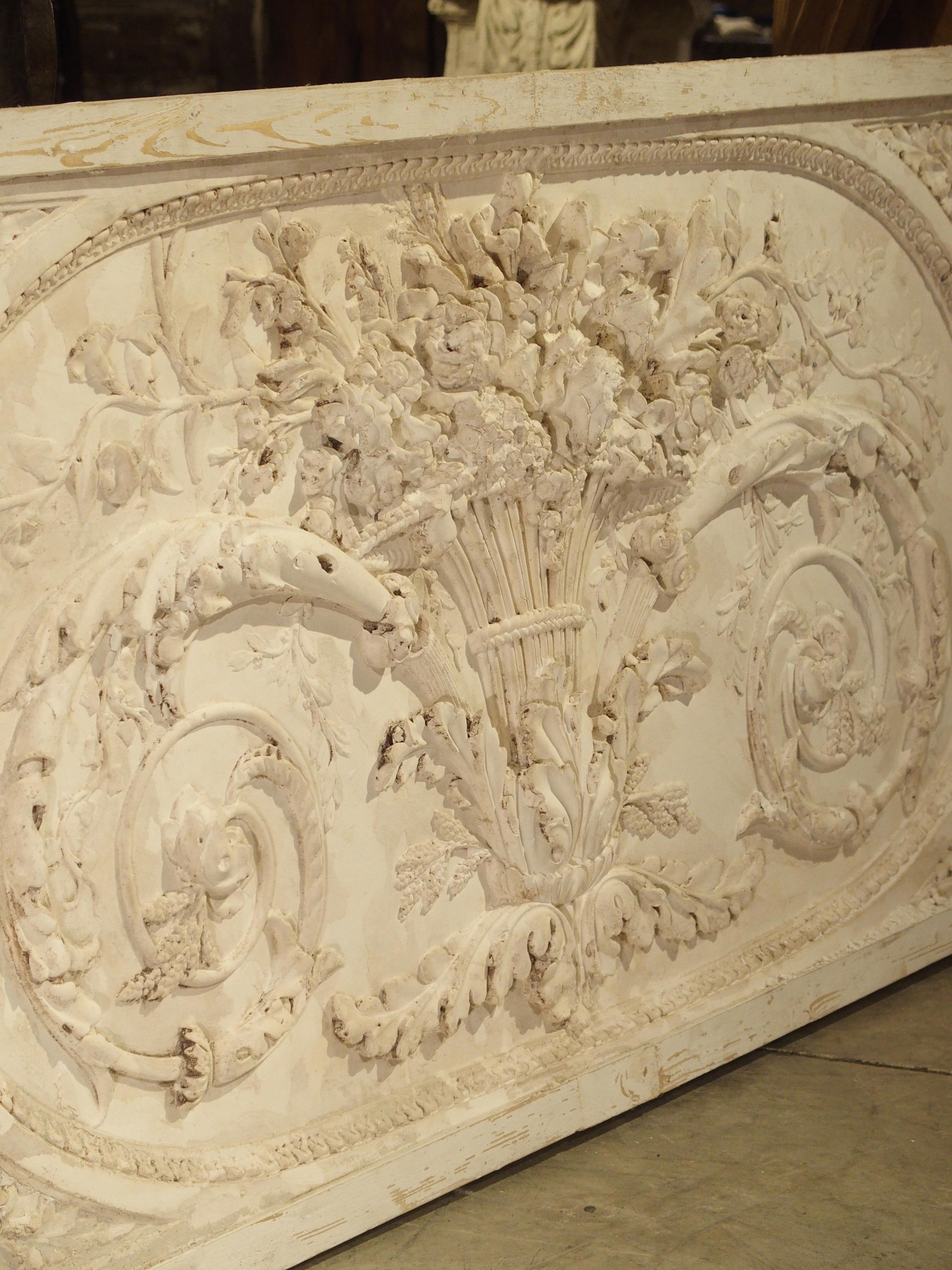 This beautiful panel is a parcel paint plaster bas relief from France. The framed plaster overdoor depicts Classic scrolling rinceau growing from a central vase. Originally, these were placed over doors in French paneled rooms. Today, they can still