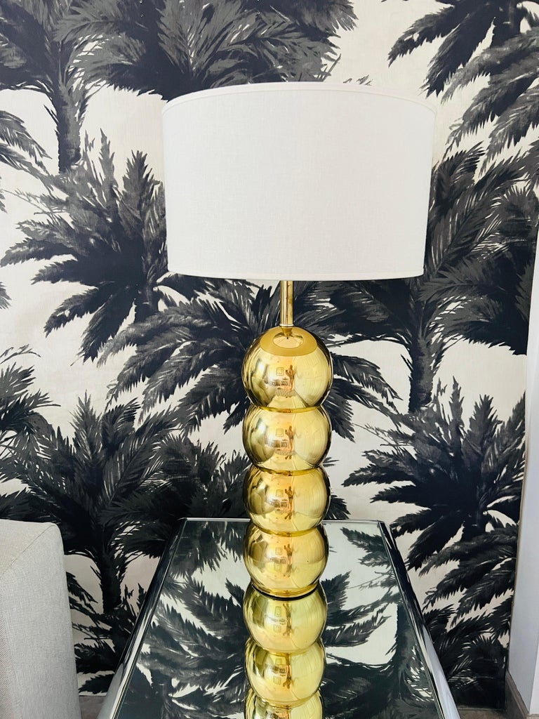 Mid-Century Modern architectural lamp comprised of stacked brass metal orbs or globes. Unique brass finish makes this lamp a rare find as similar designs from the era were mostly in chrome. Fitted with off-white linen drum shade. Adds a chic design