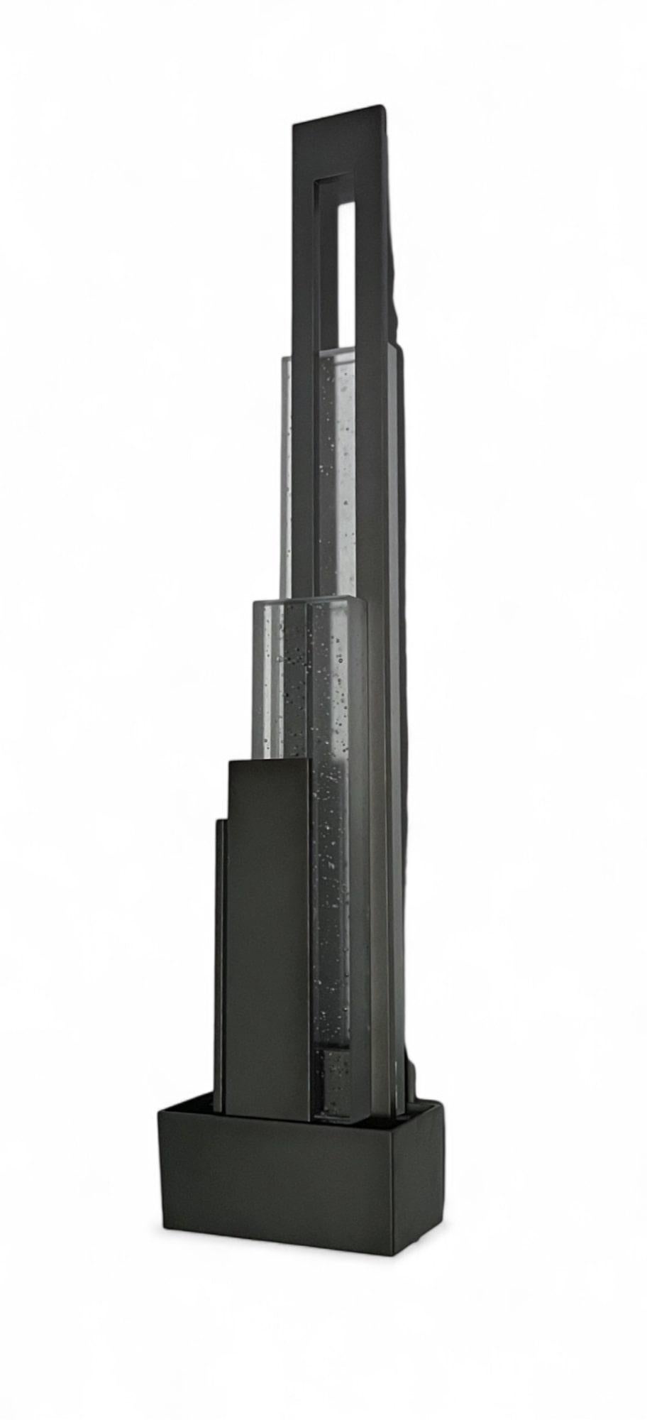 Este llamativo aplique arquitectónico es un ejemplo de iluminación escultural que fusiona a la perfección la estética modernista con el diseño arquitectónico. Inspirada en las formas imponentes del horizonte de una ciudad, esta pieza encarna una