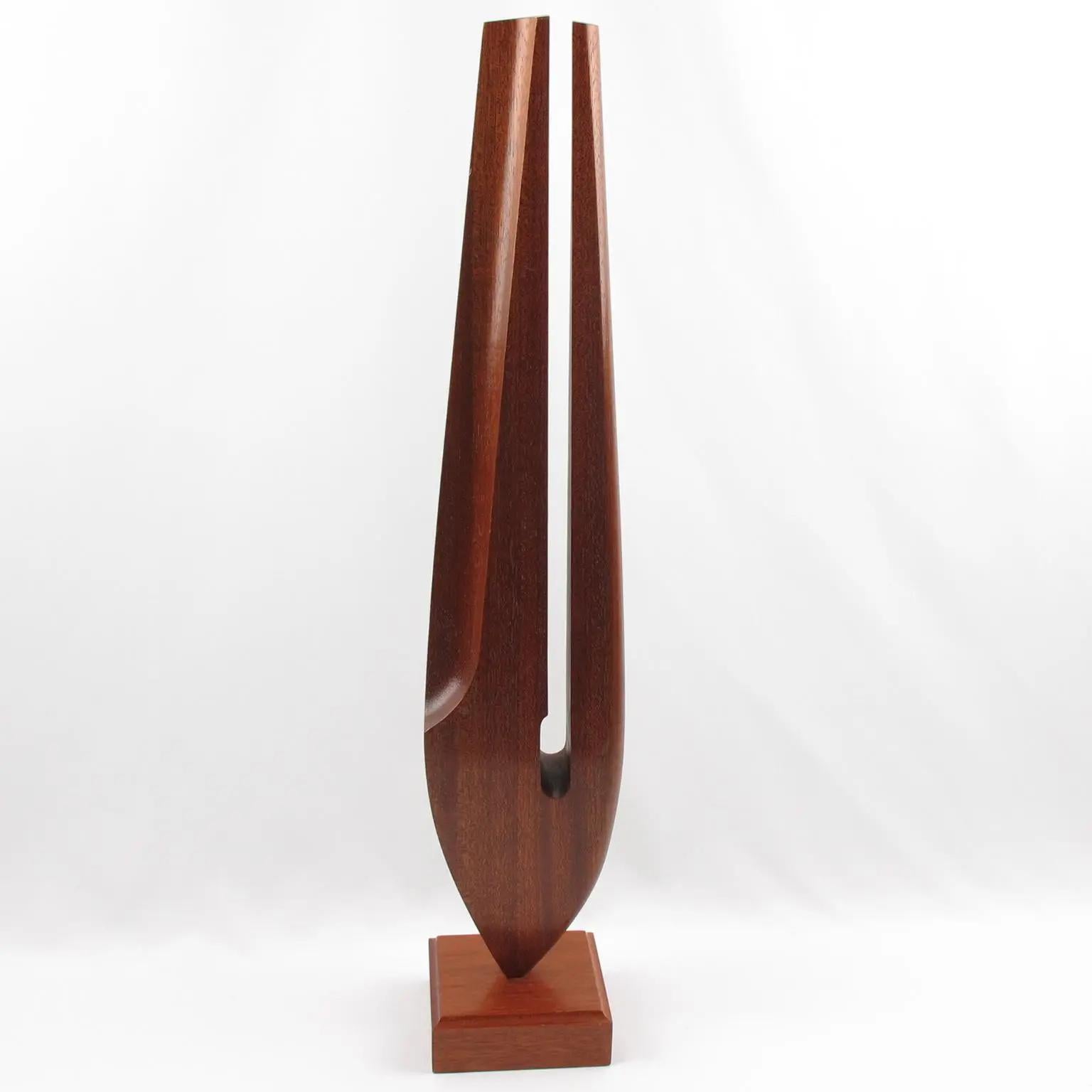 This stunning tropical wood sculpture is architecturally impressive with its stylized tuning fork design. The elongated wooden ornament sits atop a square wood base, featuring geometric lines and golden cut proportions that exude a modern and