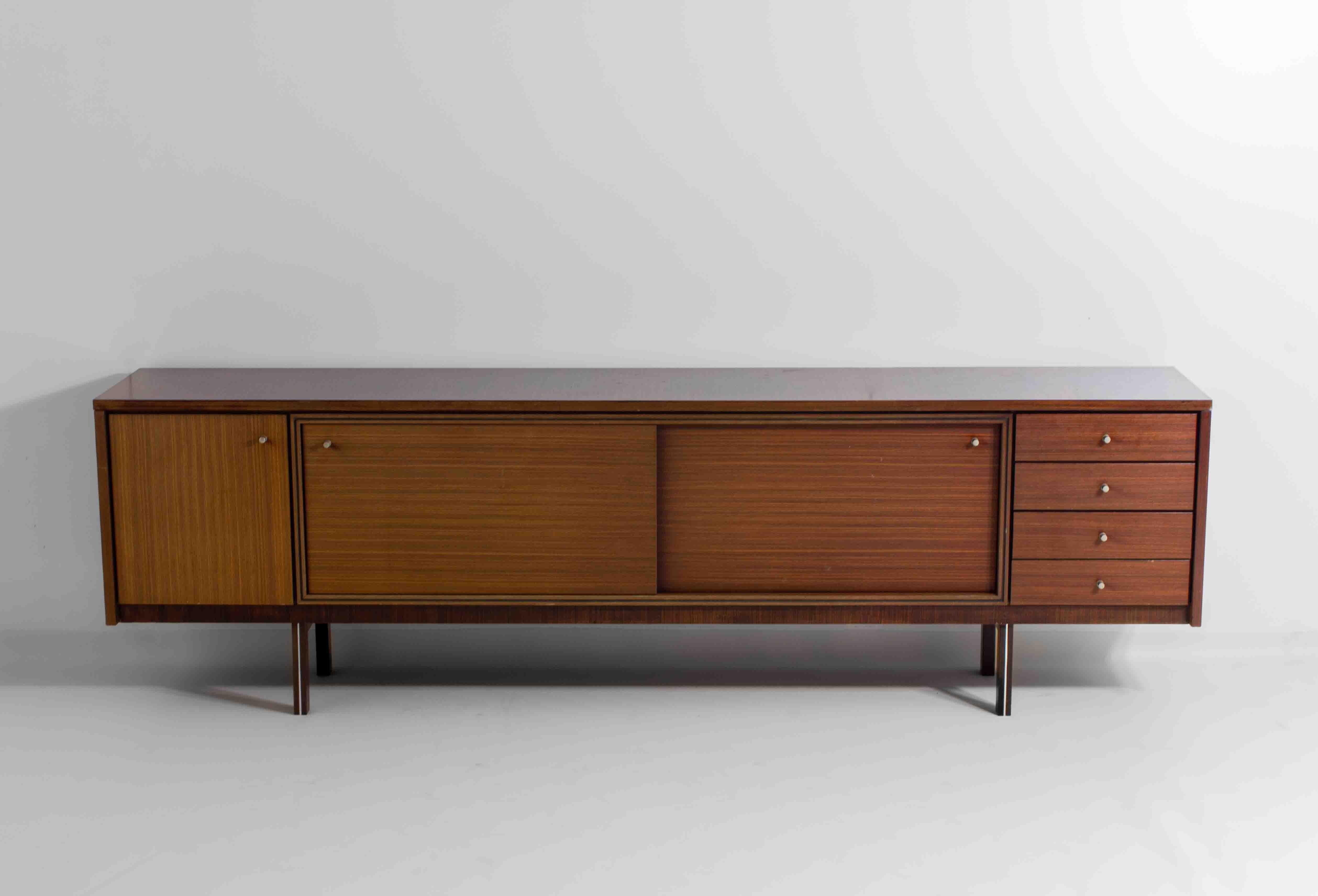 This rare and extra-long sideboard was designed by Belgian designer Pieter De Bruyne in the early 1960s. The body as well as the doors and drawers are finished in teak and feature small round aluminium handles, a signature De Bruyne sign. It was