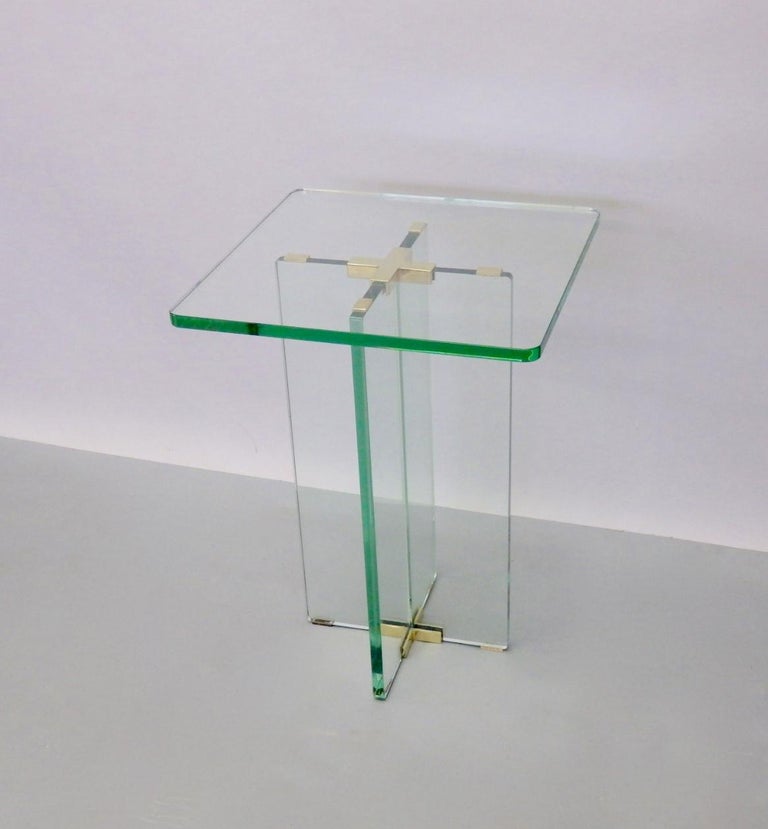 Constructed with four pieces of three quarter inch thick celadon green edge glass. Elements are joined with polished cast brass hardware. This side table is an elegant clean simple architectural design having cross base supporting glass top.