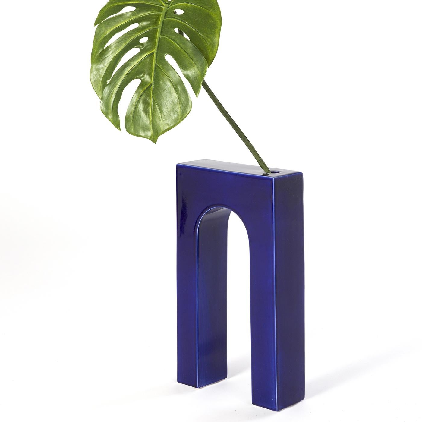 Entirely crafted of ceramic with a glossy blue finish, this vase is inspired by the metaphysical paintings by De Chirico. Its strong architectural presence and hypnotic allure create a stunning frame for floral decorations to place in the small hole