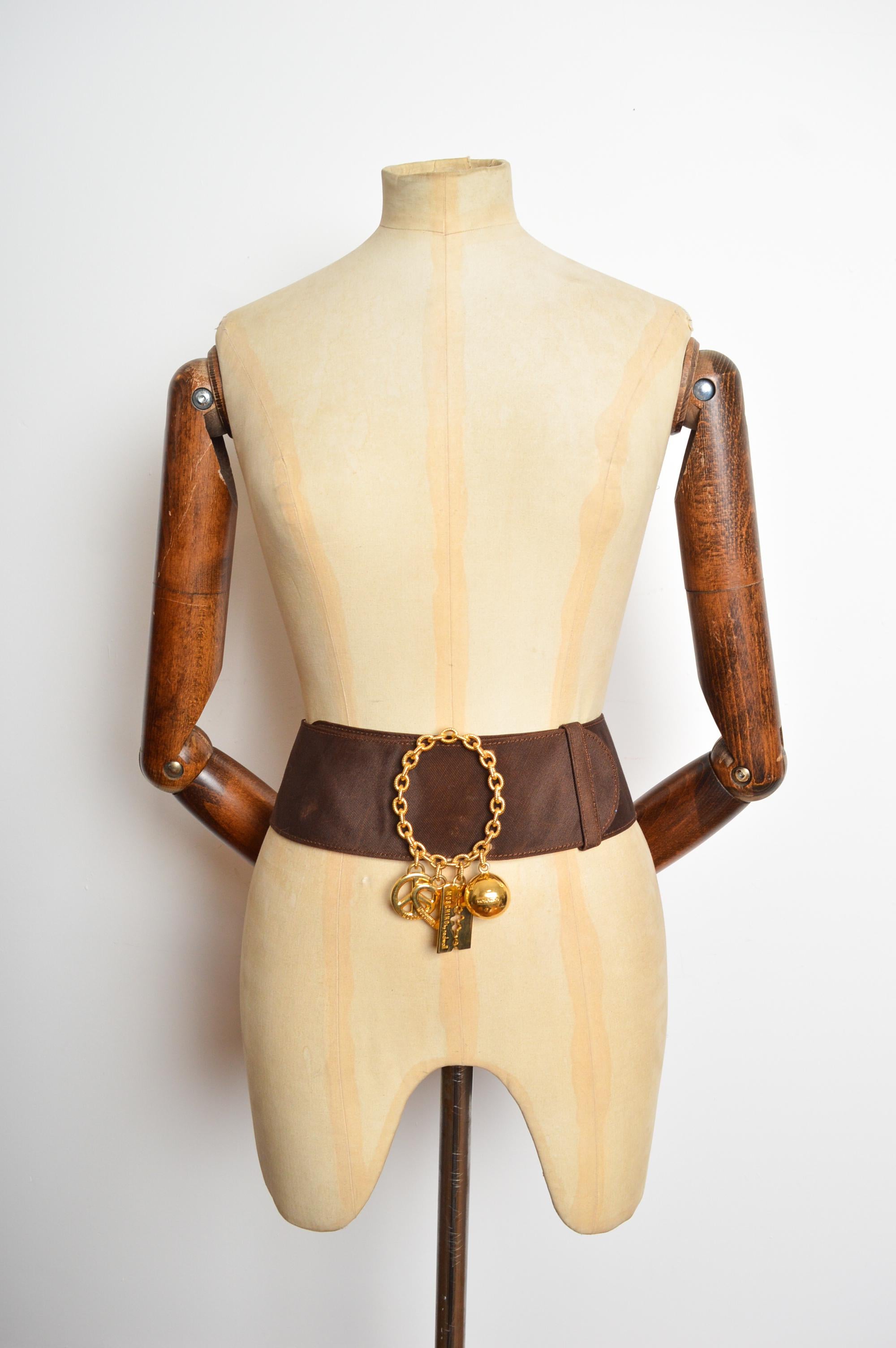 Cintura d'archivio anni '80 Moschino in jacquard marrone e charme dorato
Una favolosa cintura anni '80 di Moschino by Redwall. Caratterizzata da una grande fibbia decorativa a catena circolare, con charme d'oro in rilievo 