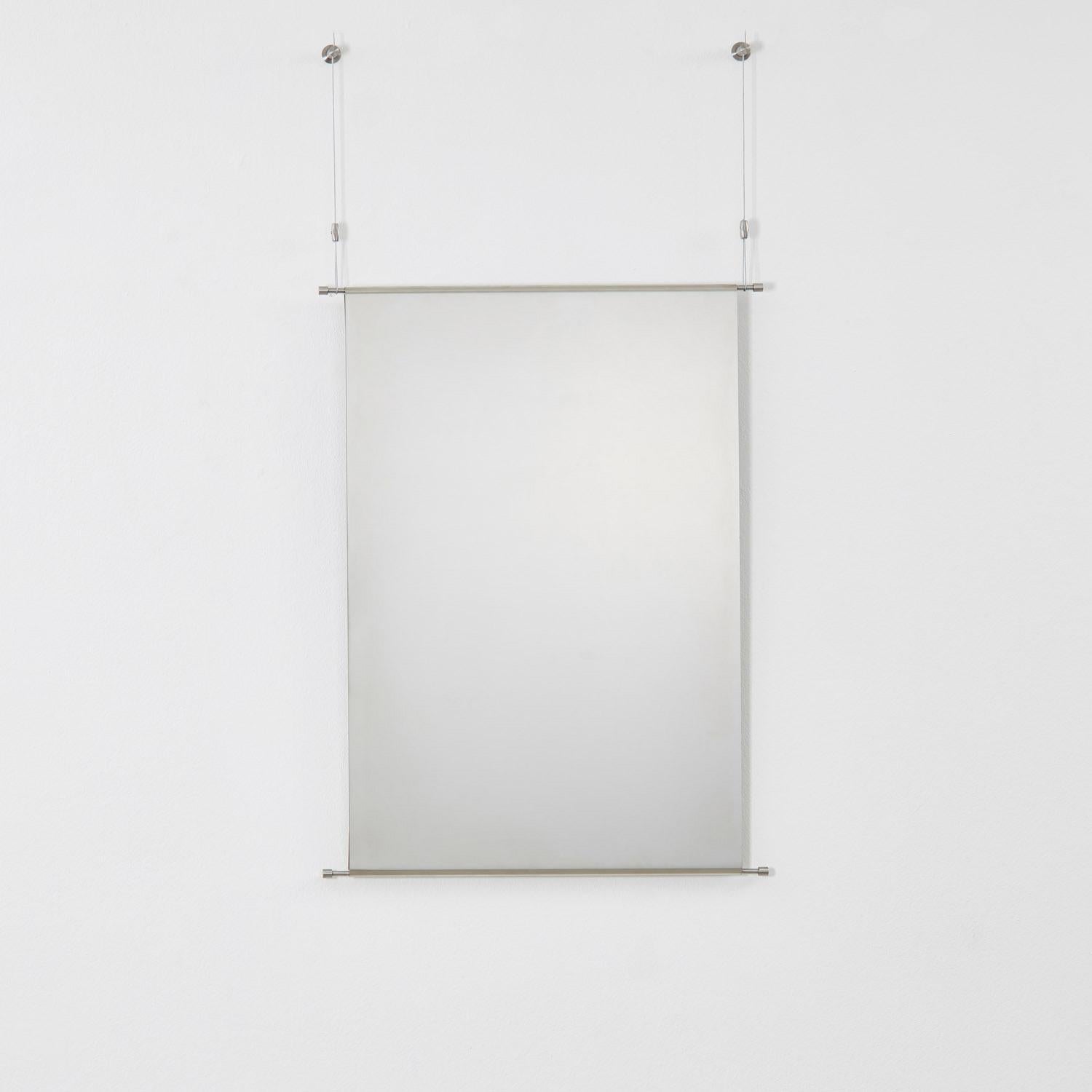 Fabriqué sur commande par Archive for Space, Mirror 001 traite l'acier inoxydable avec la fluidité d'un tissu. Les ourlets roulés permettent de suspendre le miroir à deux fils minces, troquant la rigidité du métal contre un sentiment d'apesanteur et