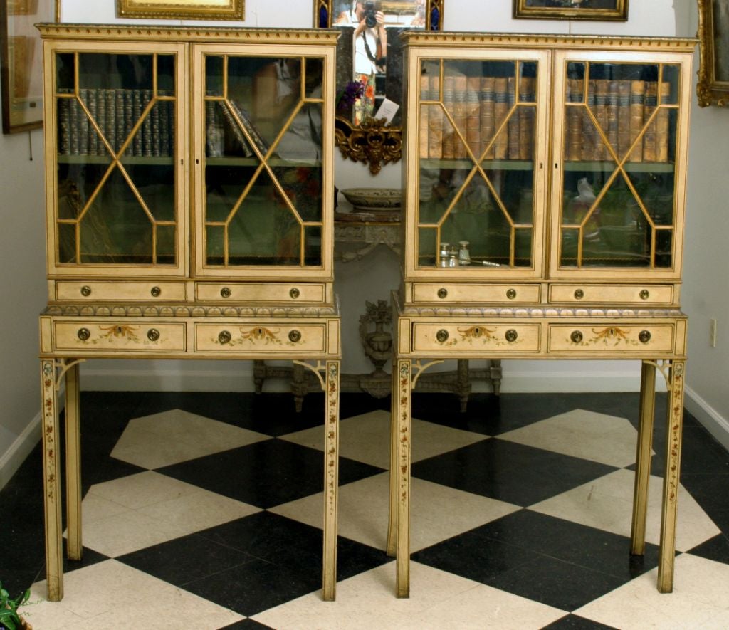 Each with a molded cornice above a pair of diamond mullioned glazed doors opening to a shelf, a two pair of drawers, raised on square legs headed by pierced brackets, painted with ribbons, flowers and trading vines<br />
<br />
Provenance: