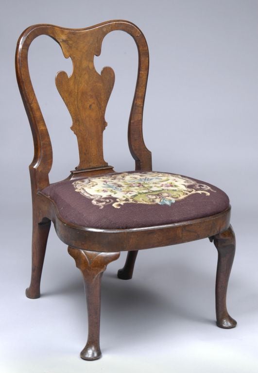 Period Queen Anne walnut side chair having elegant vase-shaped splat, rounded seat frame, slip-in seat covered with later, but antique, needlework on shaped and lightly carved cabriole legs with pad feet.