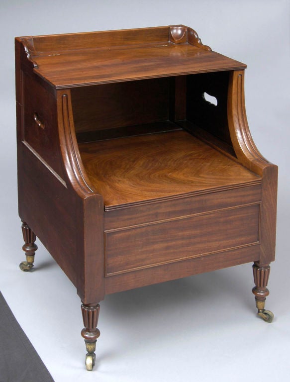 Superb quality Georgian mahogany Lancashire bedside commode with molded sloped front rails, pierced sides for carrying and raised on reeded legs with brass casters. The flat surfaces are hinged and lift to reveal the original ceramic chamber pot