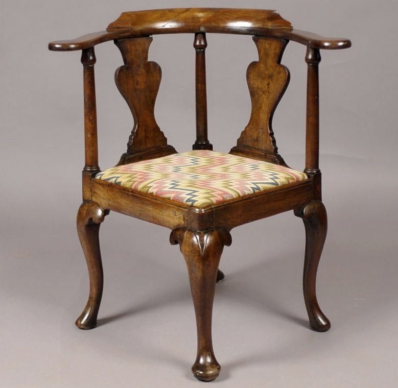 An early 18th century Corner Chair in walnut, mounted on four cabriole legs ending in pad feet for a balanced appearance from any perspective. The exposed seat rail framing a removable upholstered seat, amd the U-shaped back rail supported by three