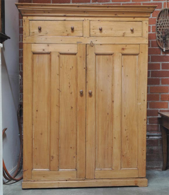 This cabinet has two panelled doors spanning the full width and are situated below two useful drawers. Imported from England and dateing from the late Victorian period, circa 1880. Solidly constructed, with a waxed finish, this cabinet will add