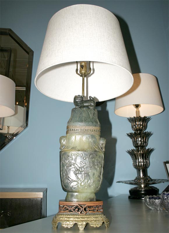 Fabulous carved jade urn form table lamp with hollowed center having a light.  Mounted to a carved teak support and a gilded bronze lower base. Signed Chasecraft on bottom. 24 HOUR HOLD ONLY.