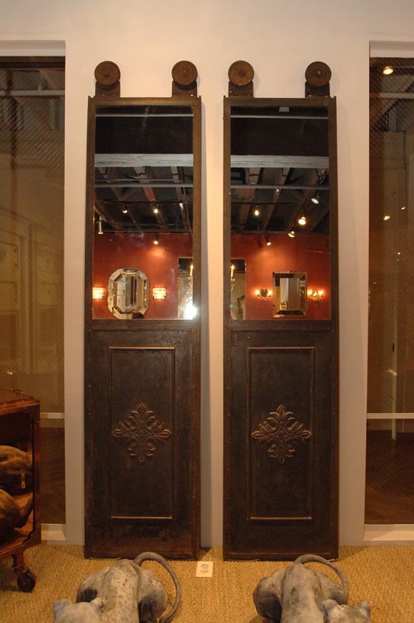 Pair of metal elevator doors with mirrored tops and medallion relief.  Salvaged from a gymnsium building in Southern California.
