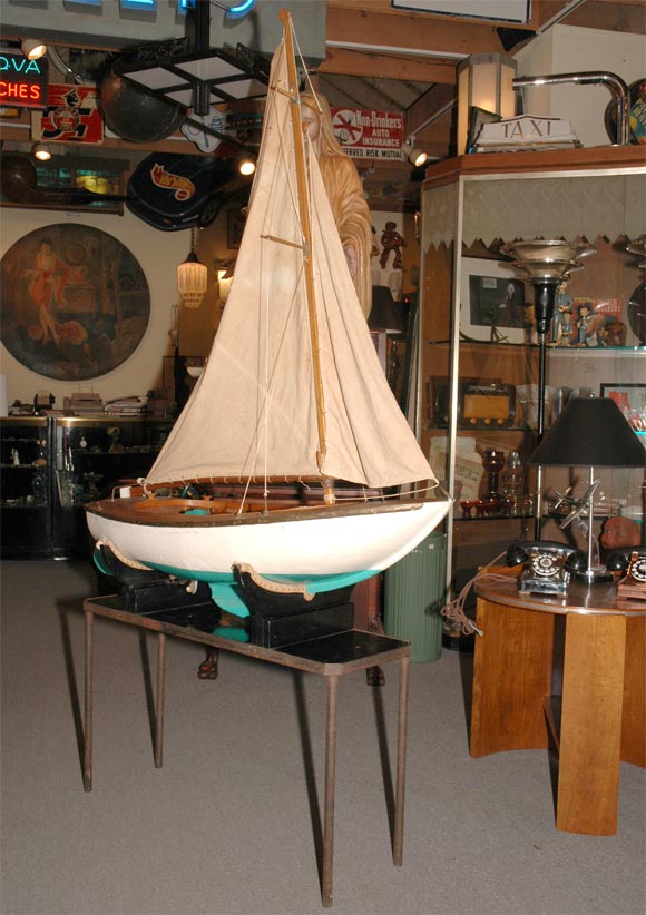 This fantastic sailboat just drips with charm! Built in the 1940's and sailed at San Francisco's Golden Gate Park, it now enjoys retirement on the hand built table stand. The hull is all planked mahogany and shows a great overall patina. The carved