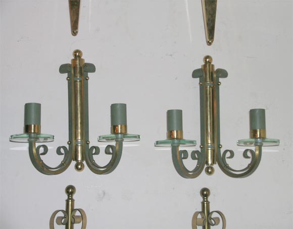 Paire d'appliques murales deco, Travail, Français, années 1940. Bronze patiné vert et doré avec des abat-jours circulaires en verre.