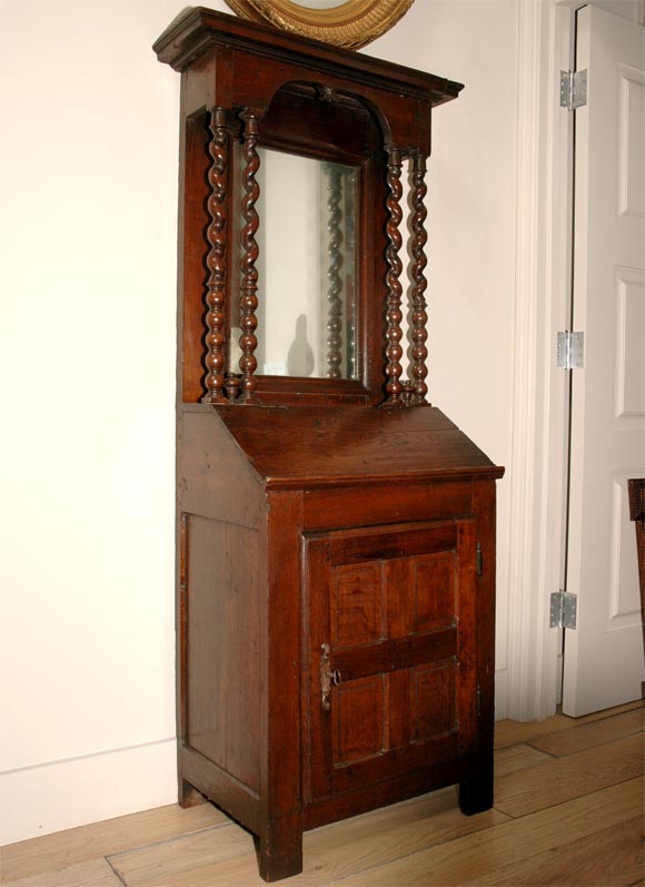 Early 18th century French petite secretaries or fall front bureau cabinet with projecting cornice and arched front enclosing a mirror and fronted with barley twist columns. The lower body has a slant front desk over a one door cabinet.