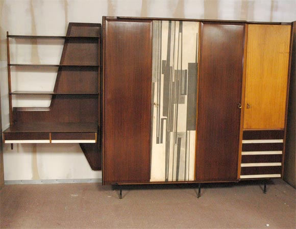 A Bedroom suite comprising an armoire with an attached desk-shellving unit,made of mahogany with details in white formica and ridged fruitwood,the monoprint door is litographed on melamine and designed by The Italian artist Mario Radice.<br