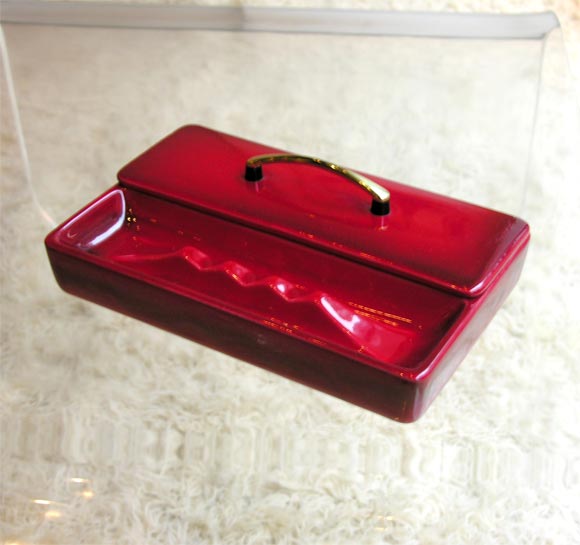Cigar case in ceramic, glazed in lustrous crimson. Half is a cigar case with lid topped by a beautiful golden handle; the other half is an ashtray. By Royal Haeger.