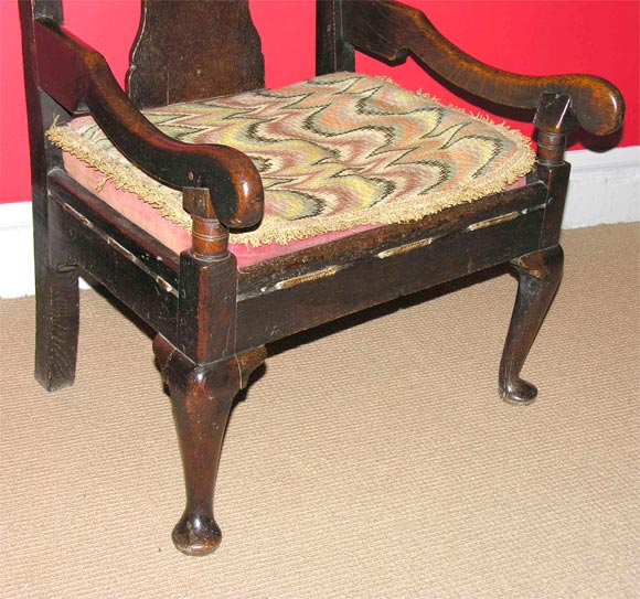 Boldly designed Scottish oak fireside/lambing armchair with paneled back on low duck-foot cabriole legs. Original flame stitch squab cushion on ropework weaving. Good rich color, circa 1760.