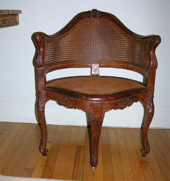 The shaped arched crestail above a caned back and seat, the seat with loose cushion cover in beige cotton over a serpentine foliate and shell-carved seatrail, on foliate-headed cabriole legs ending in scroll toes.