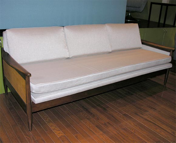 The upholstered base of this sofa lifts up slightly and then out to provide a twin-size sleep space; newly re-upholstered