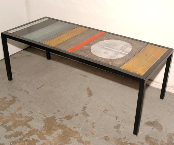 Une table basse très chic composée d'un empilement de carreaux multicolores, aux textures variées, mis en valeur par un grand carreau représentant un visage de soleil français des années 60.  Signé par l'artiste.