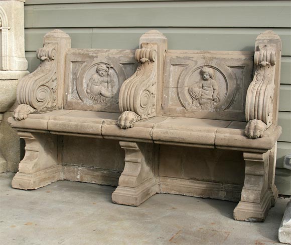 Exquisite Italian cast-stone double-seated garden seat from an English country estate, c1870. The two panelled back featuring high relief putto, the arms with acanthus scrolls and paw feet, and on plinth bases with indented quatrefoils.