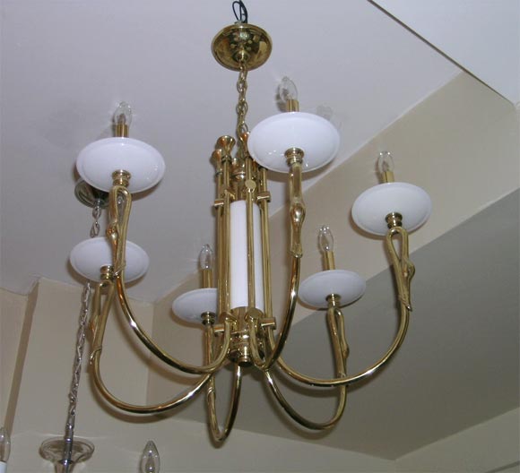 A 1950s chandelier with Deco styling. The fixture is composed of brass and white blown glass elements. The center colomn and the bobeches are made of white opaline glass. Each arm has a decorative swan. Six lighting sources.