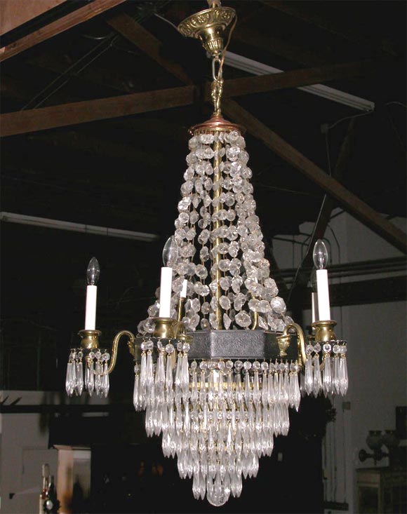 This elegant chandelier is very decorative.  It is made up of many different materials.All the drops are there, the circular band is iron, the cups are brass and it is capped in brass.