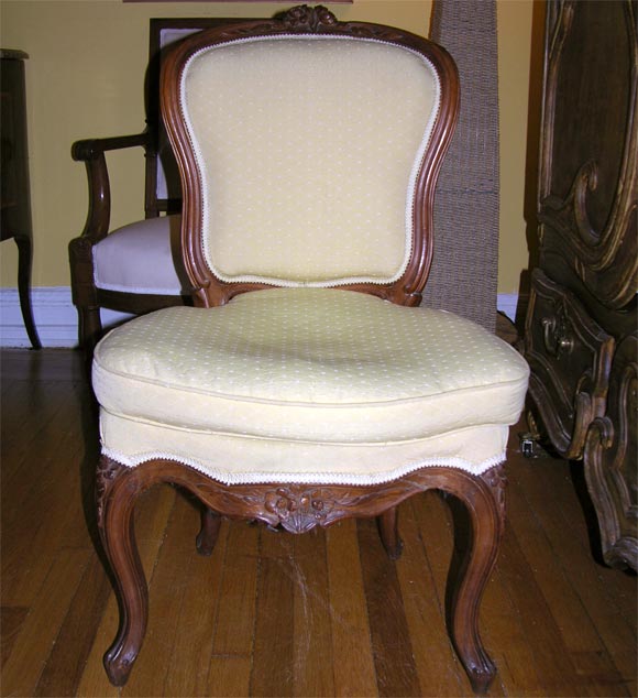 each chaise en cabriolet with cartouche-shaped backrest carved with flowerheads and foliage, the serpentine seat carved to match the top rail, raised on cabriole legs. Minor variations to carving. 2 with yellow tissue, 2 with cream.