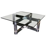 Glass cocoktail table resting on a lucite and chrome steel base.