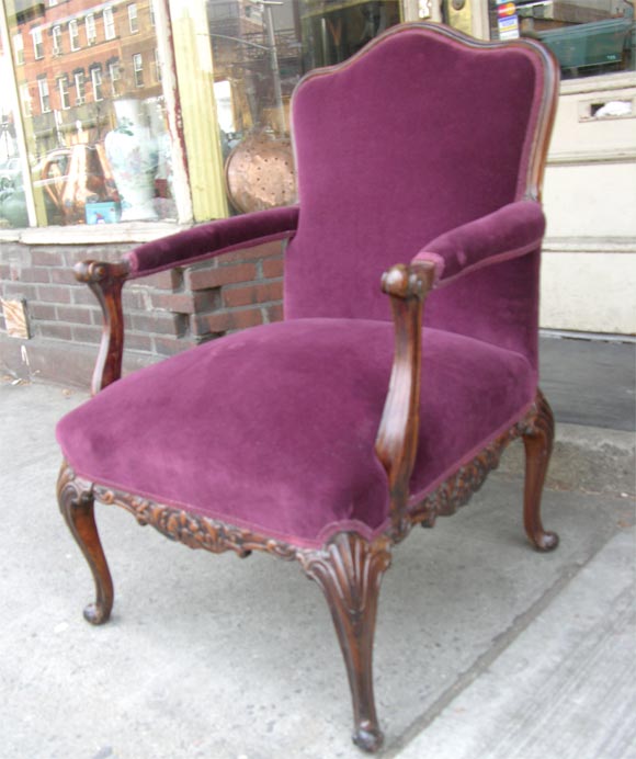 A English carved mahogany scrolled arm library chair with plush purple velvet upholstery.,