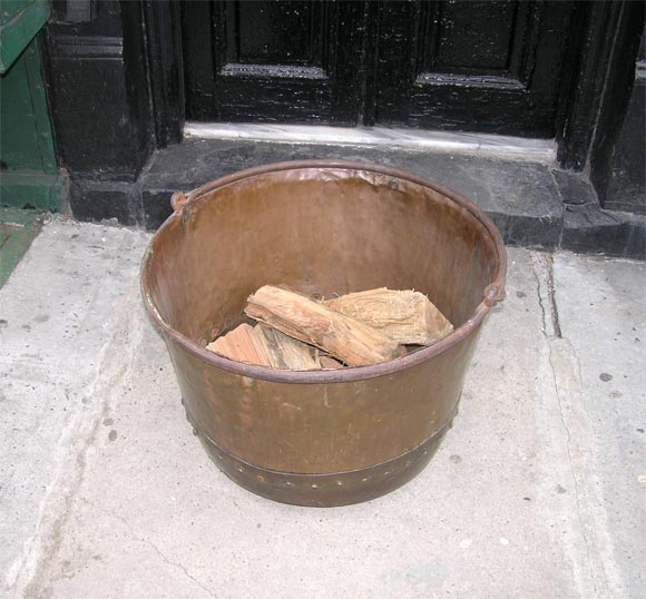 Wonderful overscale English 19th c. hand-hammered and rivetted copper cauldron now used as log container for large country house fireplace.  With original wrought iron hanging handle.