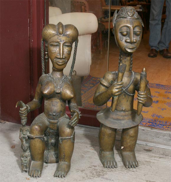 Pair of bronze figures from the Ivory Coast of Africa, a young man with long knotted neck holding implements, and a  young woman with braided hair holding a staff with piggy-back figures