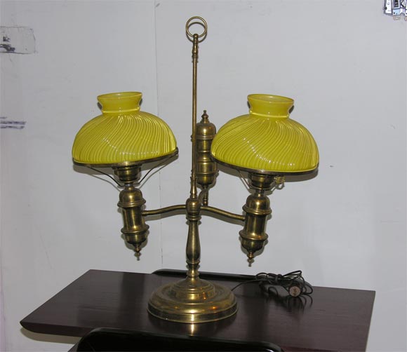 A brass student lamp with two yellow glass shades.