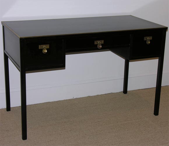 The dark mahogany desk with three draws and brass fittings and trim. Applied makers label.