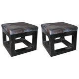 a pair of ottomans covered in natural black cowhide