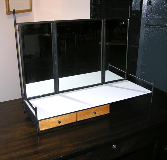 A Mid-Century Modern wing folding dresser top vanity mirror in black enameled steel with two birch drawers and white Vitrolite glass top. By Paul McCobb for Bryce Originals. U.S.A., circa 1952.