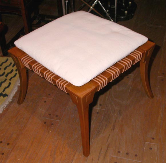 T.H. Robsjohn Gibbings stool made in lightly burnished natural walnut with leather thongs on the seat and loose seat cushion with 4 conical legs and an outside inclination.
