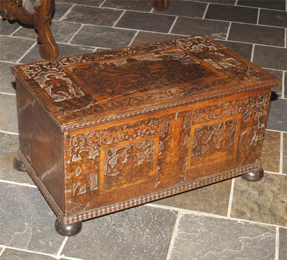 Italian baroque carved and ink-decorated walnut cassone, the rectangular hinged top above a conforming case depicting figures, raised on bun feet.