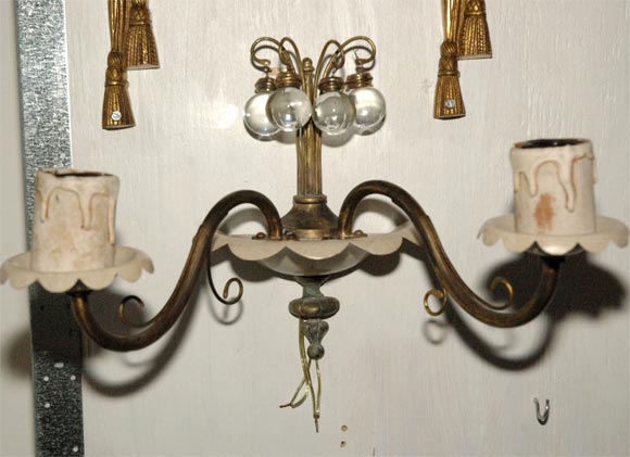 A pair of  two light wall sconces with painted and age darkened brass surfaces. Each fixture has four crystal balls suspended from brass arms reaching out to crown the top.