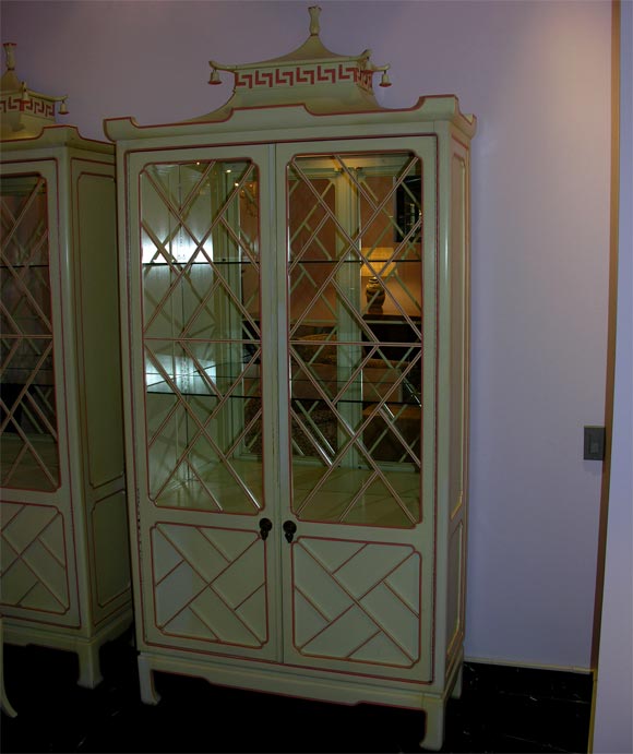 Pair of lacquered cabinets in the Chinese manner.  The cabinets each have two glass-paneled doors with open fretwork and mirrored backs.  They open to reveal two glass and three wooden shelves.  The bottom section is backed in orange crushed velvet.